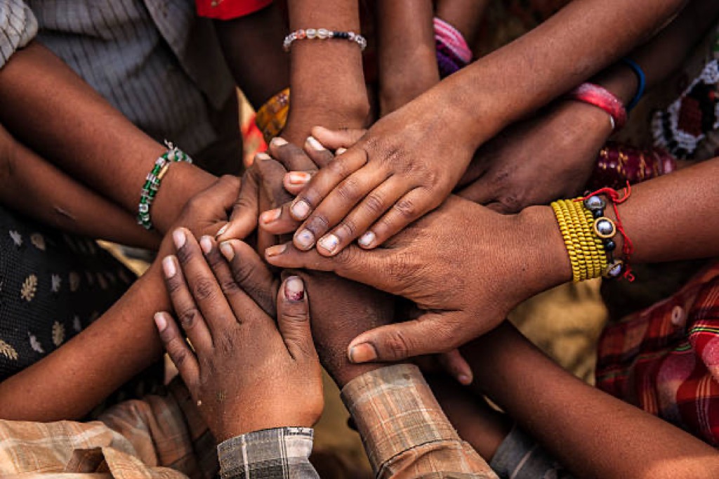 Many hands of different skin tones stacked together in a circle.